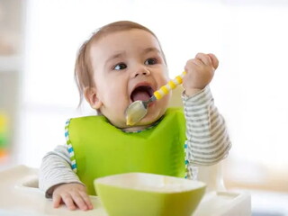 Bebé alimentándose con un babero puesto.