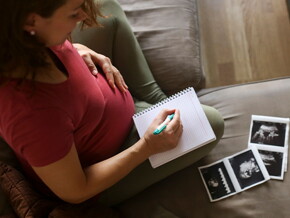 Mamá con un cuaderno mirando la ecografía de su embarazo múltiple.