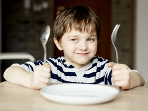 Niño alegre con sus cubiertos esperando comer alimentos constructores