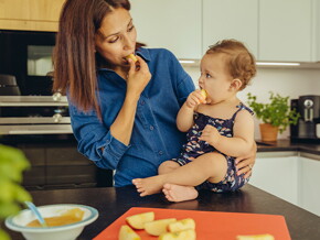 Mamá y bebé comiendo fruta en la cocina