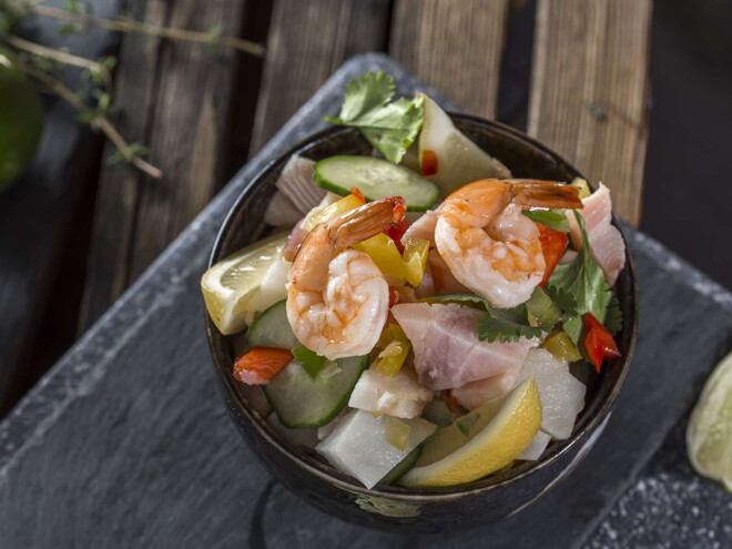 Un bowl con ceviche tropical y un limon al costado