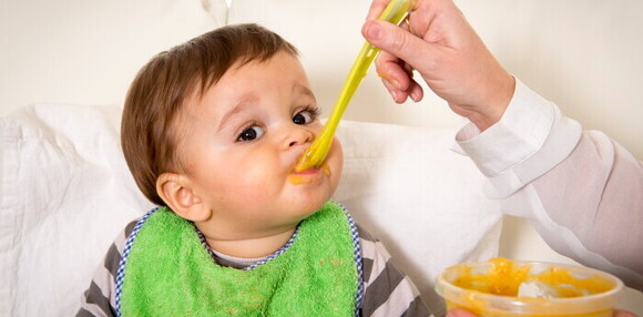 Un niño comiendo papilla después de un episodio de vómito en bebés